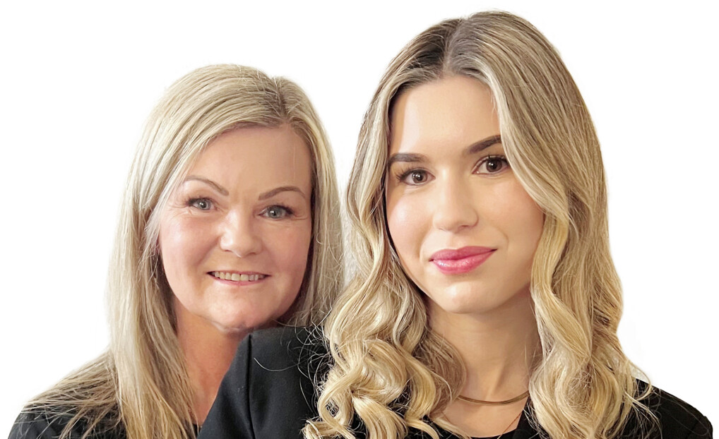 Billedet viser to personer, en mor og en datter. Begge har blondt hår, den ene med glat hår og den anden med krøllet hår. De står side om side. Baggrunden er hvid, hvilket fremhæver de to personer.