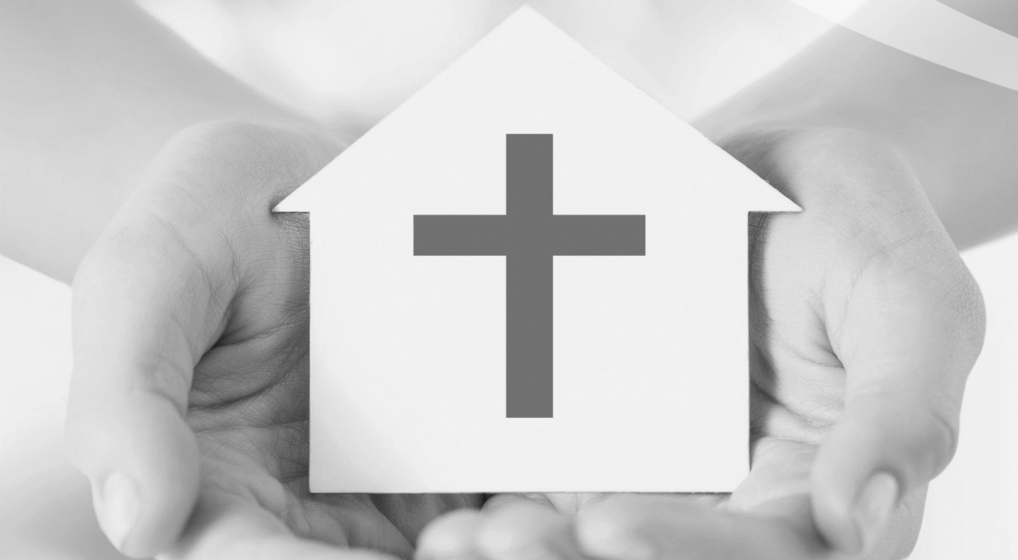 Hænder med hus med kors på