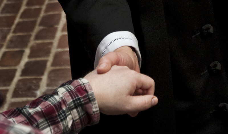 en præst og et andet mennesker holder hinandens hænder