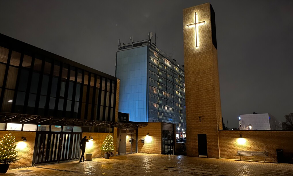 Et stort kors oplyser Strandmarkskirken, som ligger lige mellem en massiv boligblok og restauranten Kong Kebab.