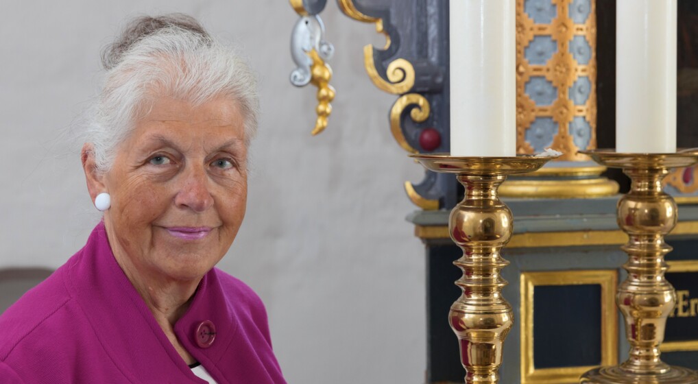 Portræt af Grethe Bahne Madsen , der står ved et alter.